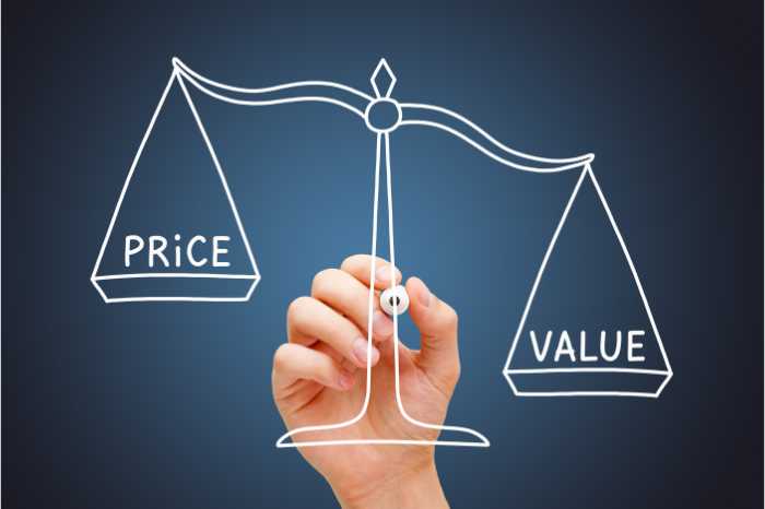at the balance of 'price' and 'value', a hand holds a writing utensil